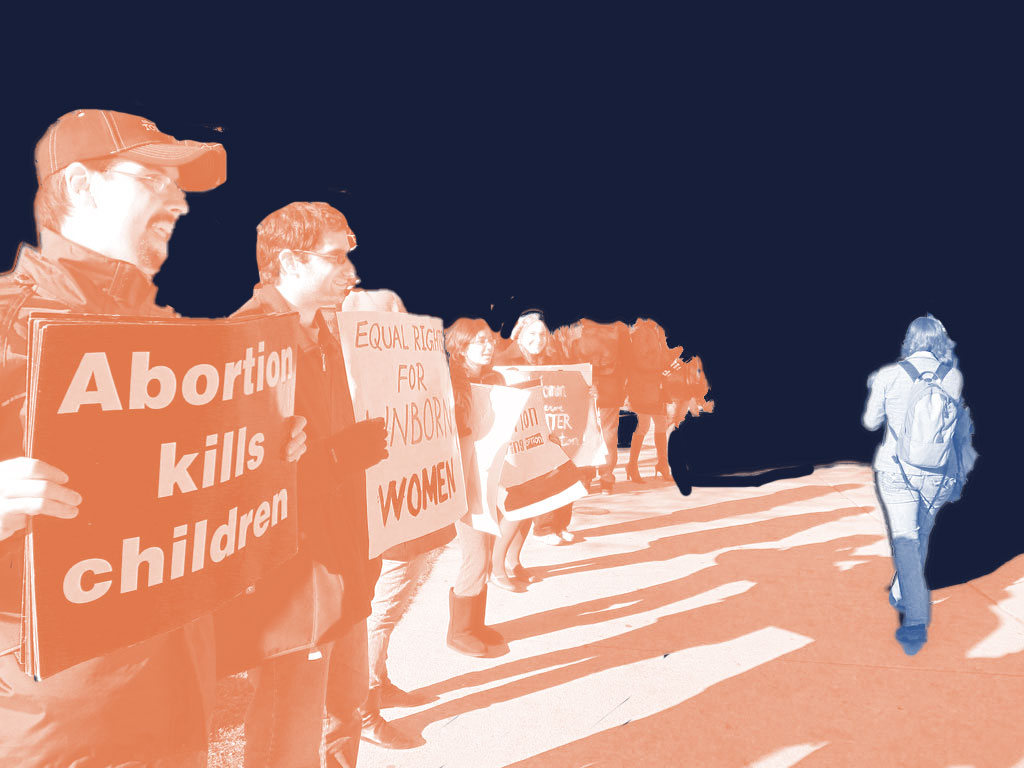 anti-abortion protesters as a women walks by